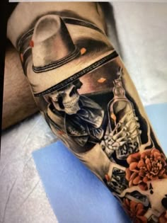 a man's arm with a skull and flowers on it, wearing a hat