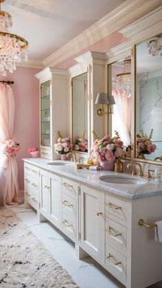 a bathroom with two sinks, mirrors and pink flowers on the counter top in front of it