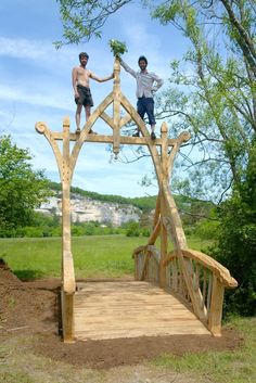 two men standing on top of a wooden bridge