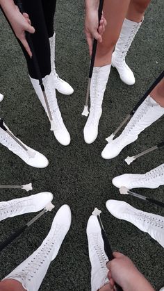 a group of people standing in a circle with white shoes and black ties on them