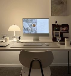 a computer monitor sitting on top of a desk next to a keyboard and mouse in front of a lamp