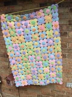 a crocheted blanket hanging on a brick wall