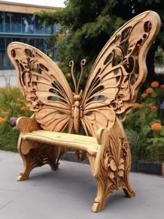 a wooden bench with a butterfly design on it's back and wings, sitting in front of some flowers