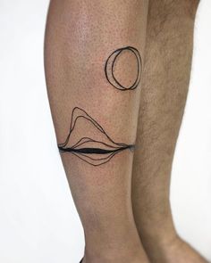 a man with a tattoo on his leg that has mountains and a moon in the sky