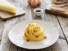 a white plate topped with spaghetti next to bread