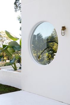 a round window on the side of a white building with palm trees in the background