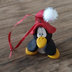 a small toy penguin with a red hat on it's head sitting on a wooden table