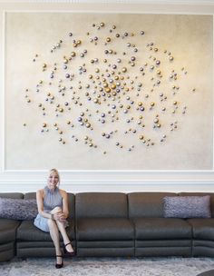 a woman sitting on top of a couch in front of a large wall art piece