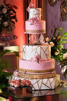 a three tiered cake sitting on top of a table next to flowers and greenery