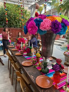 the table is set with colorful flowers and candles for an outdoor party or special occasion