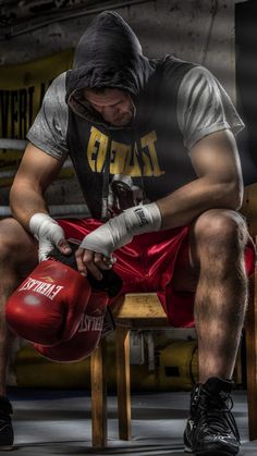 a man sitting on a chair wearing boxing gloves and holding a punching glove in his hand