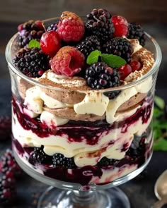 a trifle with berries and whipped cream in a glass dish on a black table