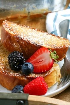 two slices of french toast with berries and powdered sugar on top, sitting on a plate