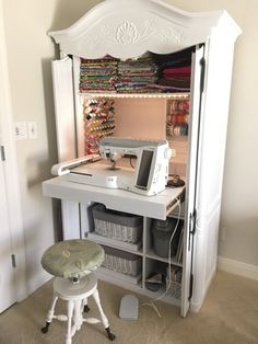 a sewing machine sitting on top of a desk next to a white cabinet filled with fabric