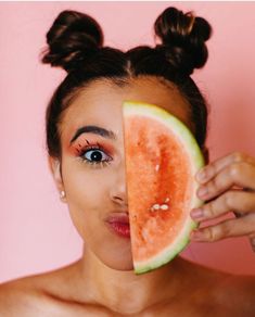 a woman holding up a slice of watermelon to her face