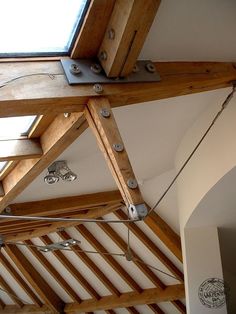 the ceiling is made up of wood beams and metal brackets, with a skylight above it