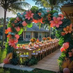 an outdoor table set up for a party with balloons and flowers on the arch over it