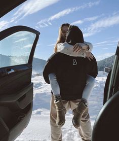 a man and woman are kissing in the back of a car on snow covered ground