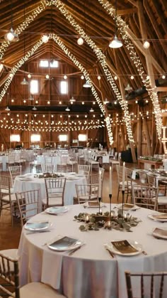 the inside of a barn with tables and chairs set up for a formal dinner or reception