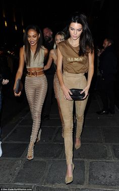 two women walking down the street at night with one carrying a purse and another holding a purse