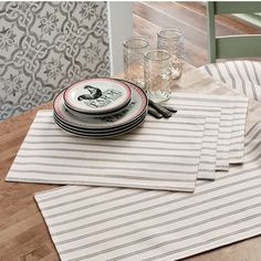 the place setting is ready to be served on the dining room table with striped placemats