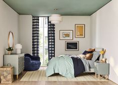 a bed room with a neatly made bed next to a dresser and chair in front of a window