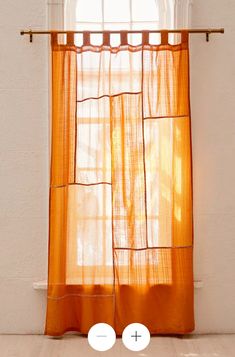 an orange curtain hanging from a window with two circles on the bottom and one circle at the top