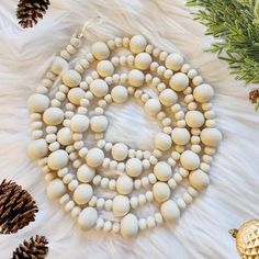 a white beaded necklace with pine cones and ornaments around it