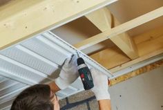 a man in white gloves is using a drill to fix a metal beam on the ceiling