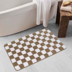 a brown and white checkered bath mat on the floor next to a bath tub