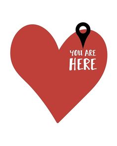 a red heart with the words you are here on it and a black pin in the middle