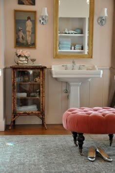 a bathroom with a vanity, mirror and footstool on the floor in front of it