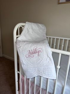 a white crib with a personalized baby blanket on the top and bottom rails