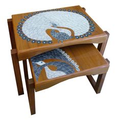 two wooden tables with mosaic designs on the top and bottom, one is holding a bird