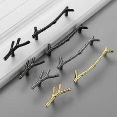 four pairs of black and gold metal hooks on the side of a white window sill