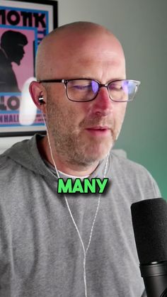 a bald man wearing glasses and headphones in front of a microphone with the words many on it