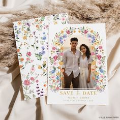 two wedding cards with flowers on them and the same photo in front of each other