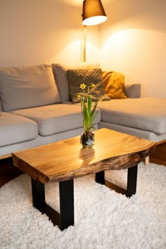 a wooden table sitting on top of a white rug in front of a living room couch