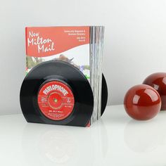 an old record and two red apples on a white countertop next to a book