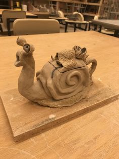 a clay sculpture sitting on top of a wooden table