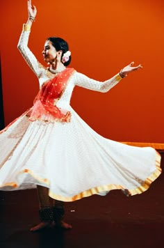 a woman in a white and red dress is dancing with her arms spread out to the side