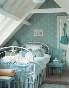 a bedroom with a bed, chair and window in the attic style room that has blue wallpaper