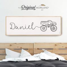 a bed with a wooden headboard that has a monster truck drawn on it