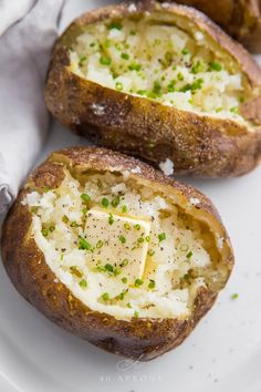 baked potatoes with cheese and chives on a white plate, ready to be eaten