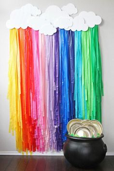 a rainbow curtain with clouds hanging from it's side in front of a potted plant