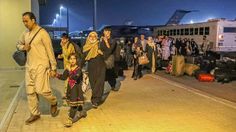 many people are walking down the sidewalk with their luggage bags and suitcases in hand