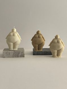 three ceramic figurines sitting next to each other on top of a marble block