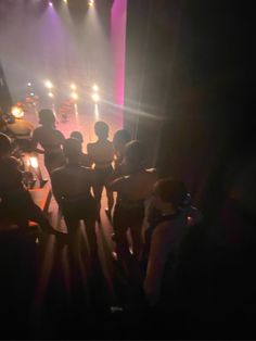 a group of people standing in front of a stage with lights on it's sides