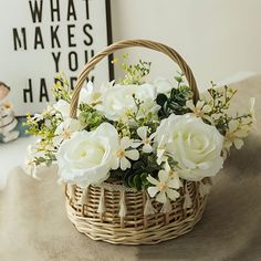 a basket filled with white flowers sitting on top of a table next to a teddy bear