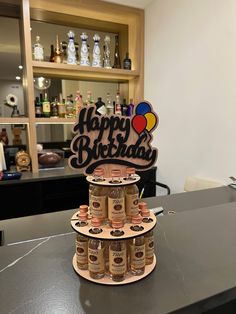 a birthday cake made out of beer bottles on top of a counter with a happy birthday sign in the background